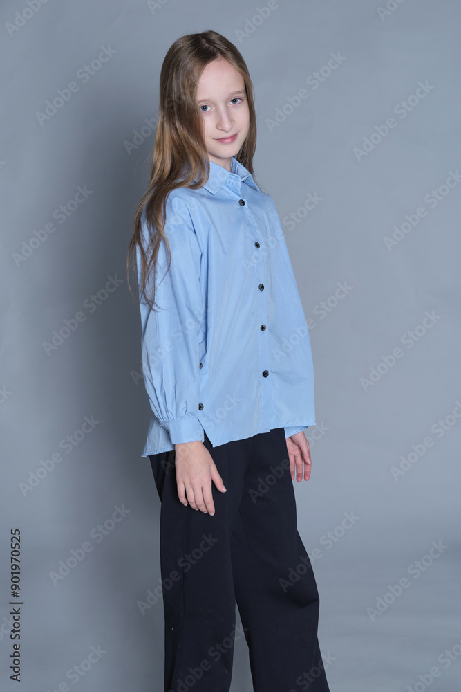 A young girl in a light blue shirt and black pants stands confidently with a gentle smile, her head slightly tilted. The photo emphasizes her youthful charm and relaxed confidence. A young girl in a light blue shirt and black pants stands confidently with a gentle smile, her head slightly tilted. The photo emphasizes her youthful charm and relaxed confidence.
