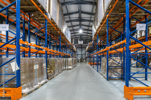 Spacious Warehouse Interior With Tall Racking Systems Displaying Stacked Pallets in Business Environment.The interior of a large warehouse features high racking systems filled with neatly stacked pall