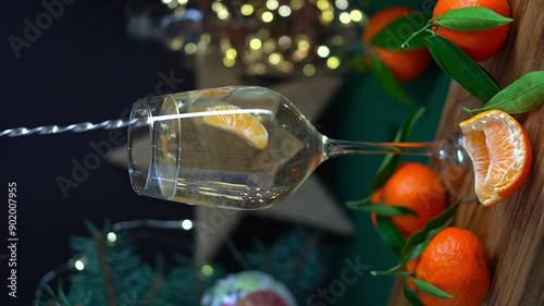 Sparkling wine with tangerine is stired in wineglass on table with mandarins fir brunch and garland