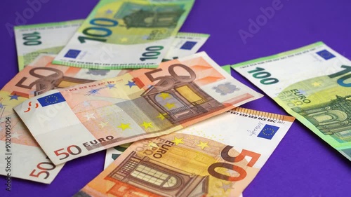 Money falling on table. Dropping lot of one hundred and fifty Euro paper banknotes on purple desk