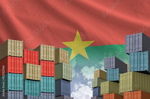 Burkina Faso flag and big stack of shipping cargo containers in docks with sky background close up photo