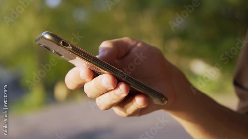 A man is texting on his smartphone in the park
