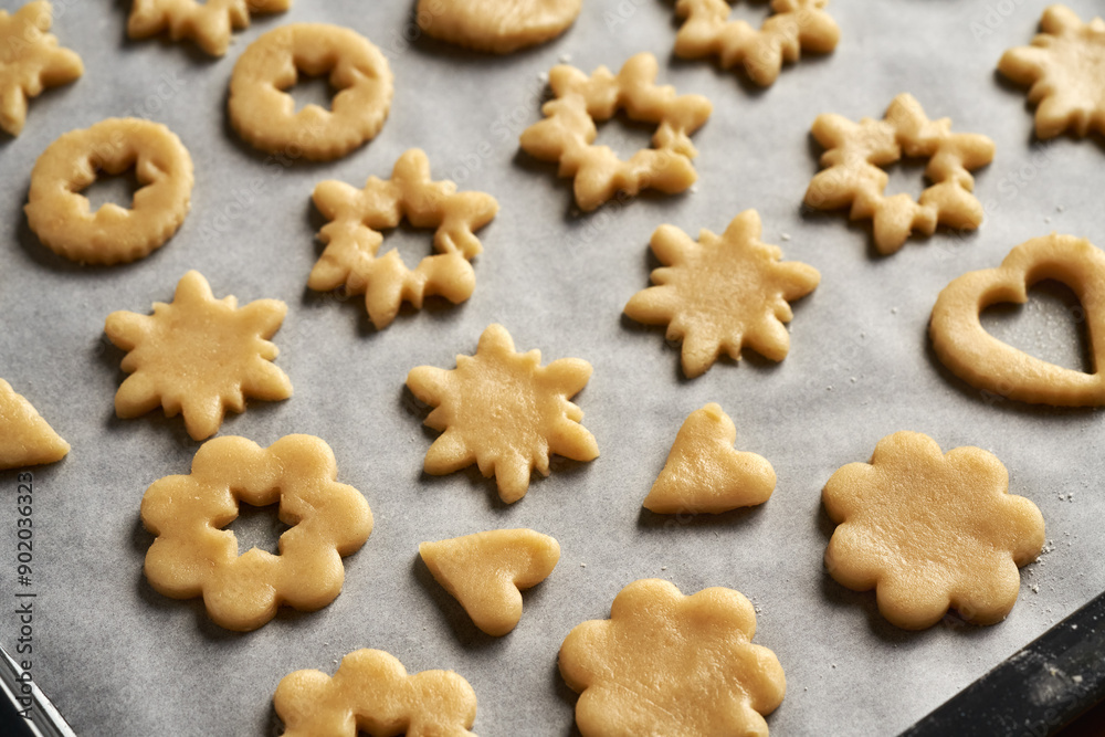 Shapes made of raw pastry dough on baking paper - preparation of homemade Linzer Christmas cookies Shapes made of raw pastry dough on baking paper - preparation of homemade Linzer Christmas cookies