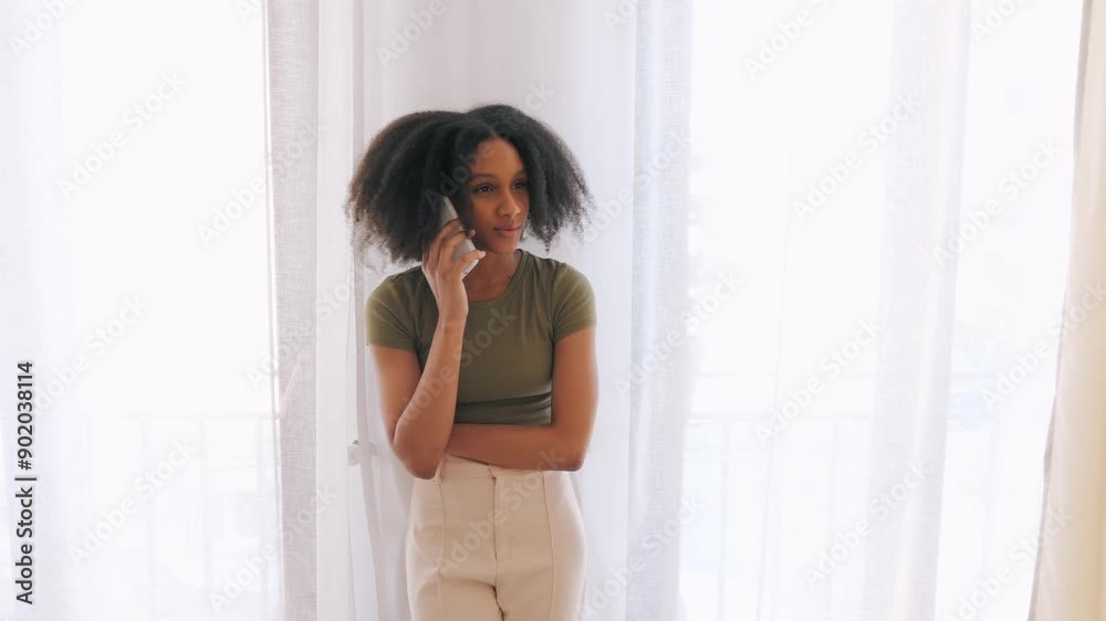 African American young lady standing and talking on smartphone with thoughtful expression. Bright indoor setting with natural light. Concept of communication, technology, connection, or everyday life. African American young lady standing and talking on smartphone with thoughtful expression. Bright indoor setting with natural light. Concept of communication, technology, connection, or everyday life.