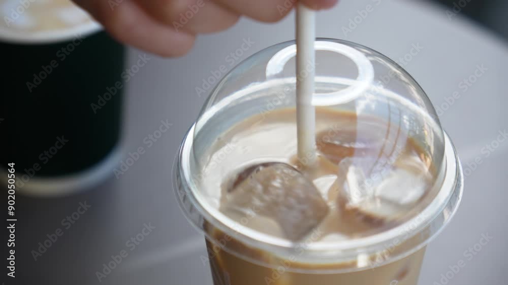 A woman's hand is stirring an ice latte. Close-up A woman's hand is stirring an ice latte. Close-up