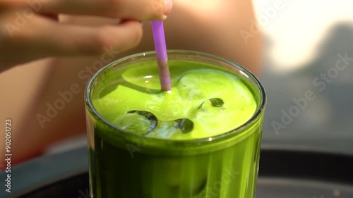 A girl stirring a matcha drink at a coffee shop
