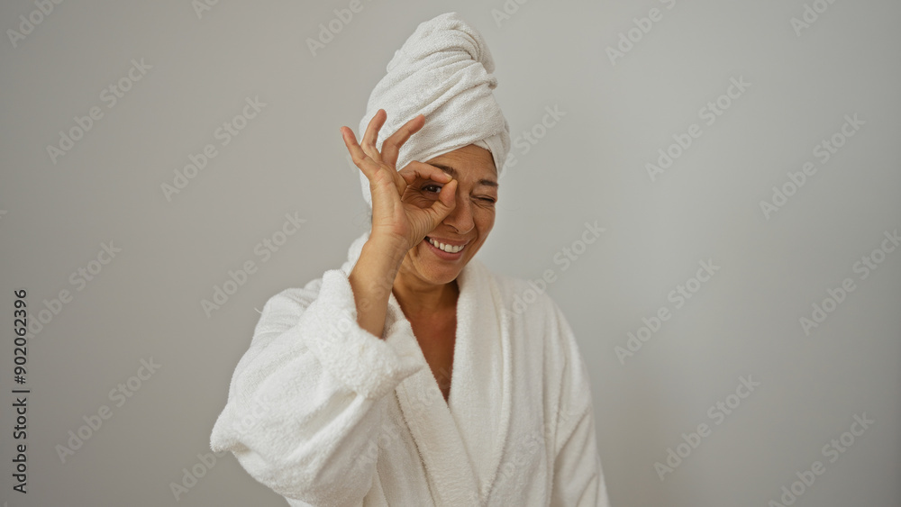 Woman wearing bathrobe and towel on head making okay gesture over white background Woman wearing bathrobe and towel on head making okay gesture over white background