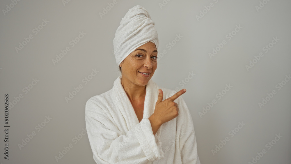 Woman pointing in white bathrobe and towel, isolated on white background, smiling, showing direction with hand, mature, beautiful, middle-aged, brunette, hispanic, female, elderly Woman pointing in white bathrobe and towel, isolated on white background, smiling, showing direction with hand, mature, beautiful, middle-aged, brunette, hispanic, female, elderly