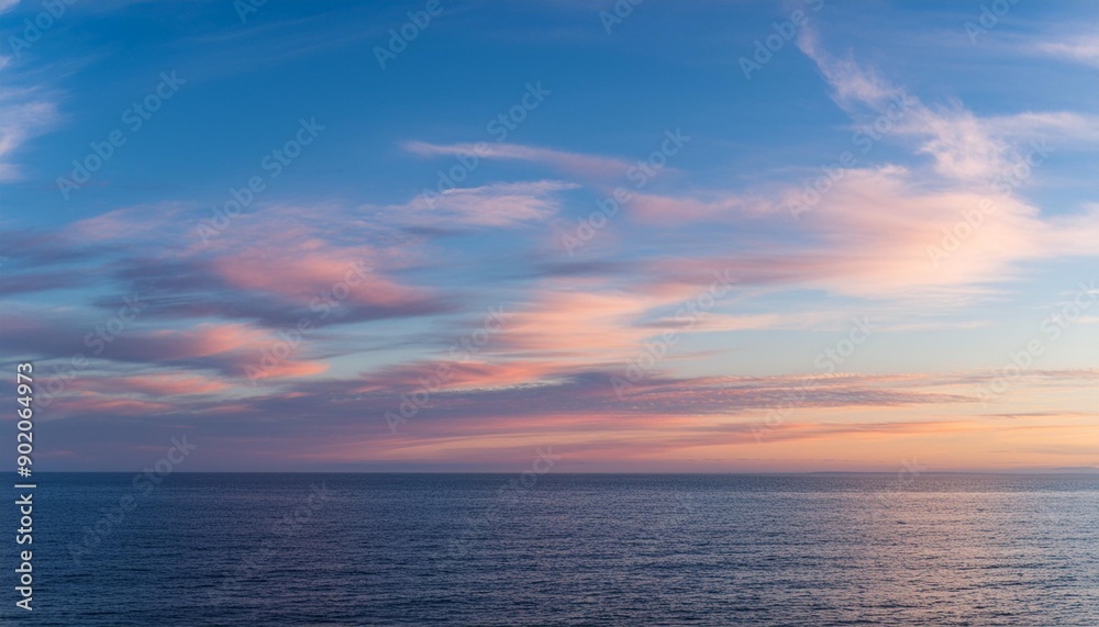 Cirrus clouds tinted pink by the sun at sunset over a calm blue ocean Cirrus clouds tinted pink by the sun at sunset over a calm blue ocean