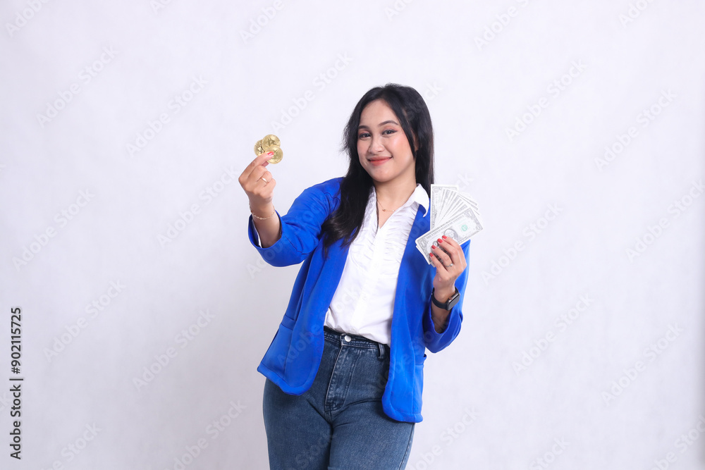 Elegant adult office woman wearing blue formal suit standing smiling to camera holding dollar and bitcoin in front isolated white background. for transaction, investment, business content Elegant adult office woman wearing blue formal suit standing smiling to camera holding dollar and bitcoin in front isolated white background. for transaction, investment, business content