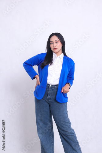 Beautiful mature Asian woman wearing a blue formal suit standing with her hands holding her waist and entering her elegant jacket pocket. for corporate, beauty, business content