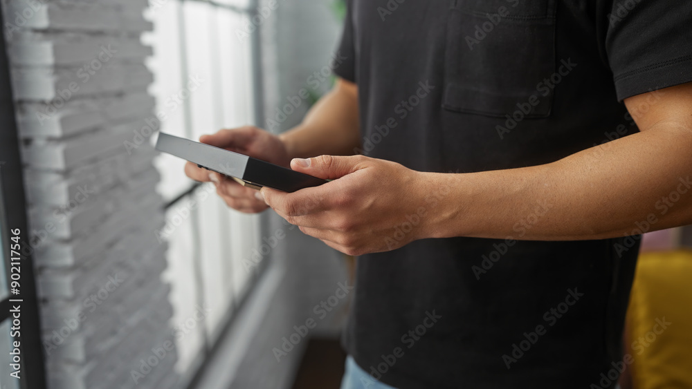 A young hispanic man in a home setting examining a photograph with focus and curiosity. A young hispanic man in a home setting examining a photograph with focus and curiosity.