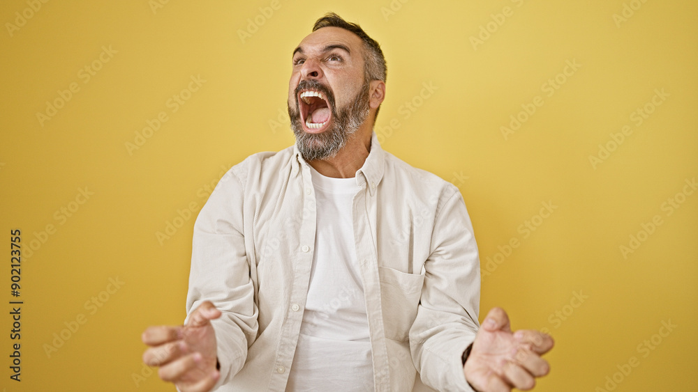 A mature bearded man expressing excitement against a yellow isolated background. A mature bearded man expressing excitement against a yellow isolated background.