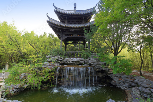 Paldal-gu, Suwon-si, Gyeonggi-do, South Korea - September 3, 2022: Summer view of pond and waterfall with a Chinese pavilion at Wolhwawon Garden of Hyowon Park
 photo