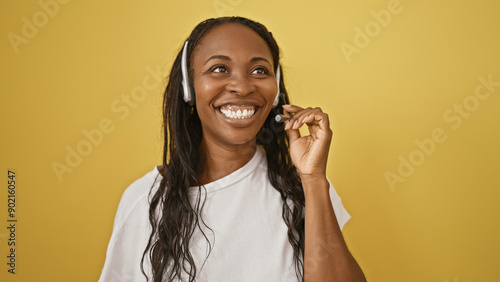 Smiling woman with headphones and microphone against yellow background speaks into headset. photo