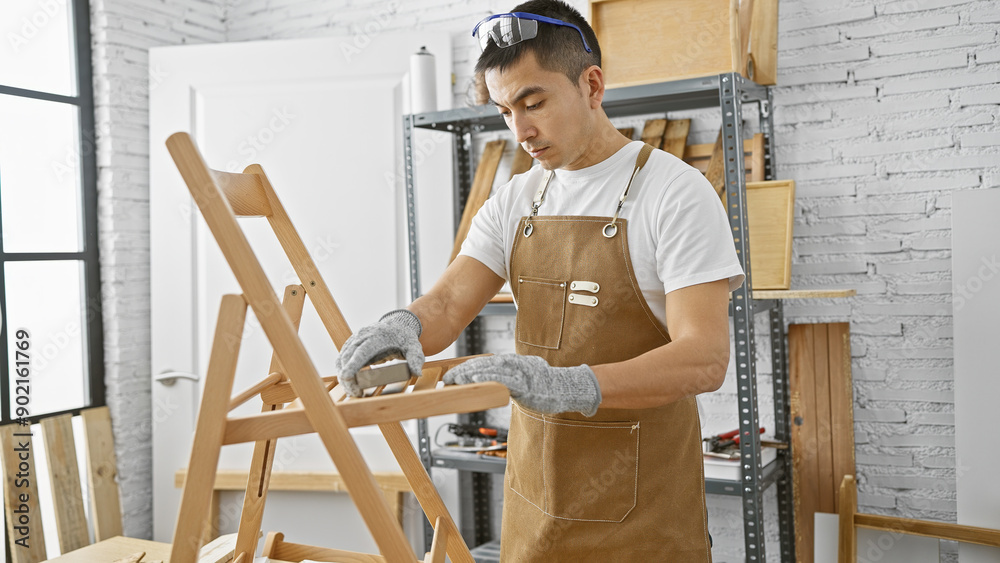 Young hispanic man sanding a wooden chair in a well-lit carpentry workshop Young hispanic man sanding a wooden chair in a well-lit carpentry workshop