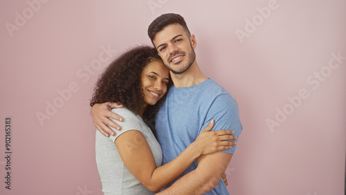 A loving couple embracing with joy against an isolated pink wall, capturing a moment of affection and togetherness.