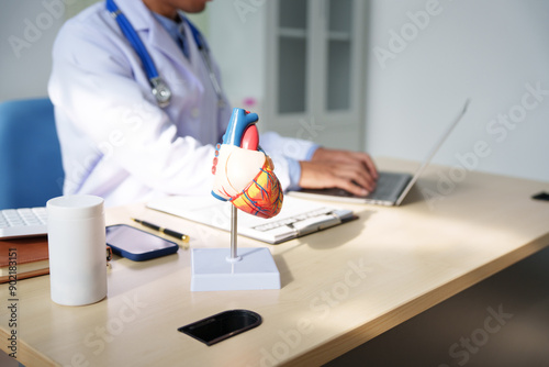 A medical doctor is working at a desk, analyzing patient data related to heart attacks and calculating medical costs to ensure accurate billing and financial management in the healthcare setting. photo