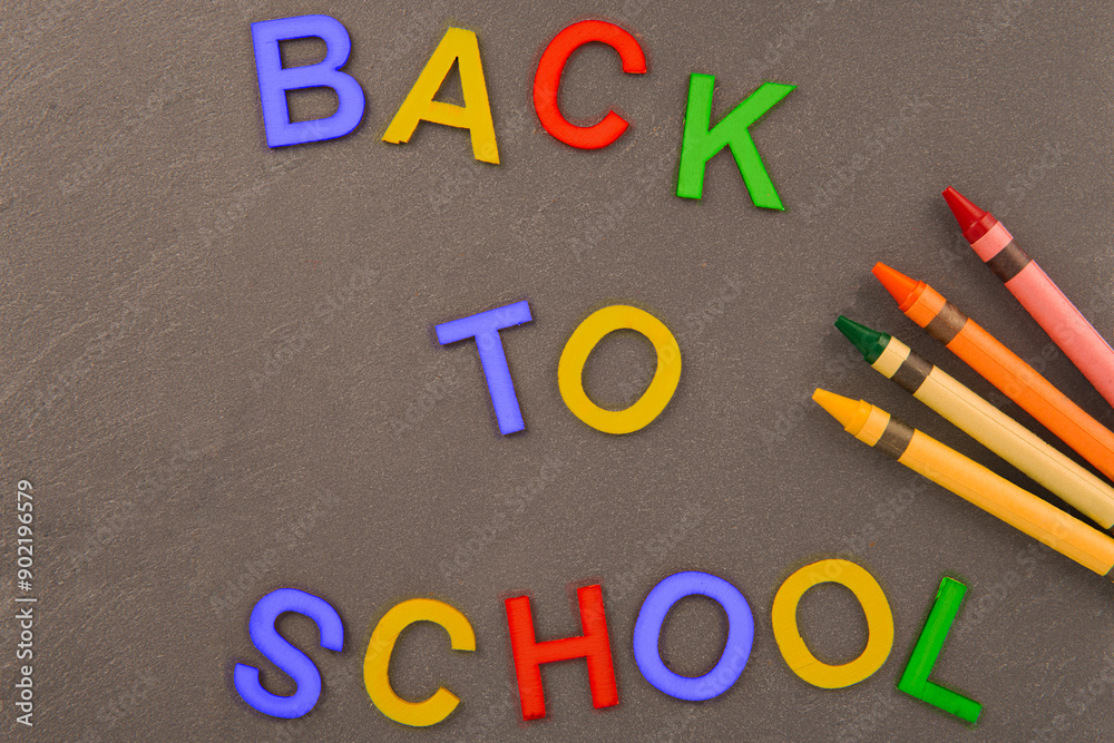 The phrase BACK TO SCHOOL written in colorful uppercase letters against a grey textured background. This image symbolizes the return to school and the start of a new academic year. The phrase BACK TO SCHOOL written in colorful uppercase letters against a grey textured background. This image symbolizes the return to school and the start of a new academic year.