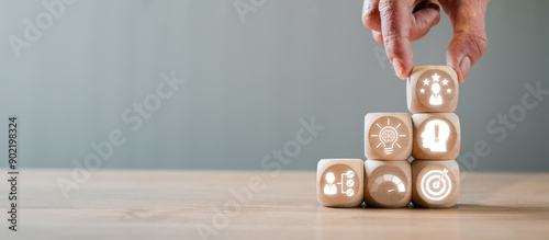 Hand arranging wooden blocks with competence concept icons, symbolizing skills, growth, and success in business and personal development.