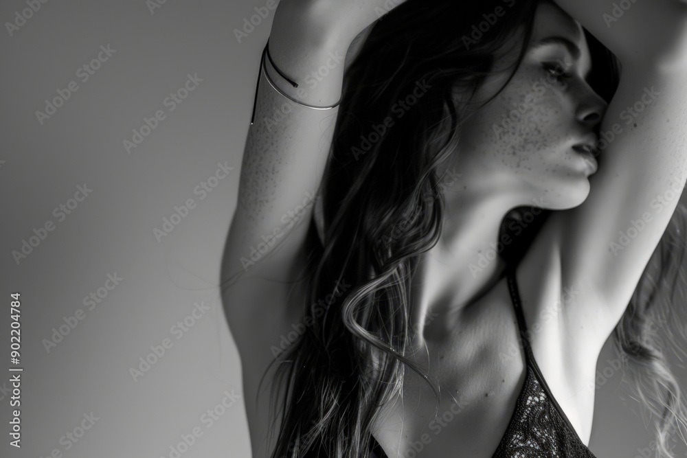 Naklejka premium Introspective Woman in Black Lace Top, Raising Hand to Neck, Against Plain Background