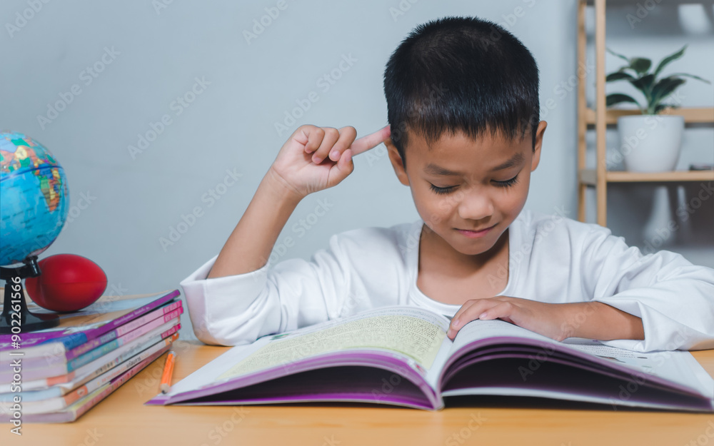 The child smile thinking sitting at table with book. Education, Childhood, People, Homework and school concept. Student learning study reading book while sitting at home. The child smile thinking sitting at table with book. Education, Childhood, People, Homework and school concept. Student learning study reading book while sitting at home.