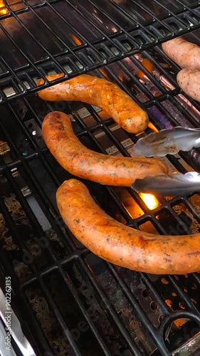 Verticle - Chef Skillfully Flipping Juicy Sausages on a Hot, Flaming BBQ Grill