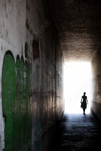 Mysterious tunnel with human figure walking toward the light.