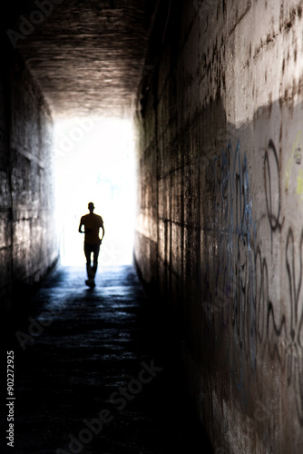 Mysterious tunnel with human figure walking toward the light.