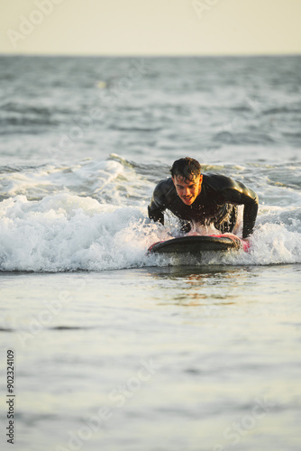 Photography Young man in wetsuit catching his first wave during his surfing lessons
