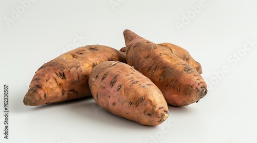 Four sweet potatoes on a white background. The sweet potatoes are various shades of brown and have a rough, textured skin. photo