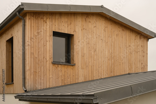 Modern architecture gable with flat roof made of metal titanium zinc and cladding made of untreated natural larch wood