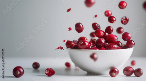 Fresh Cranberries Bouncing in Air Above White Porcelain Bowl Background for Creative Food Advertisement photo