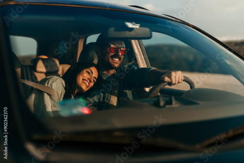 Smiling stylish woman and man sitting in a car and enjoying the ride. Woman leaned on a man's shoulder photo