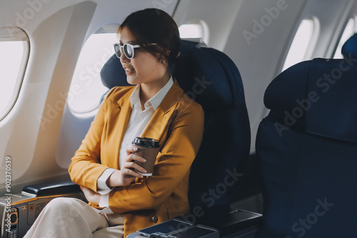A young Asian woman, seated as an airplane passenger, contemplates dollar bills, reflecting on lucrative opportunities and aspirations towards billionaire status.