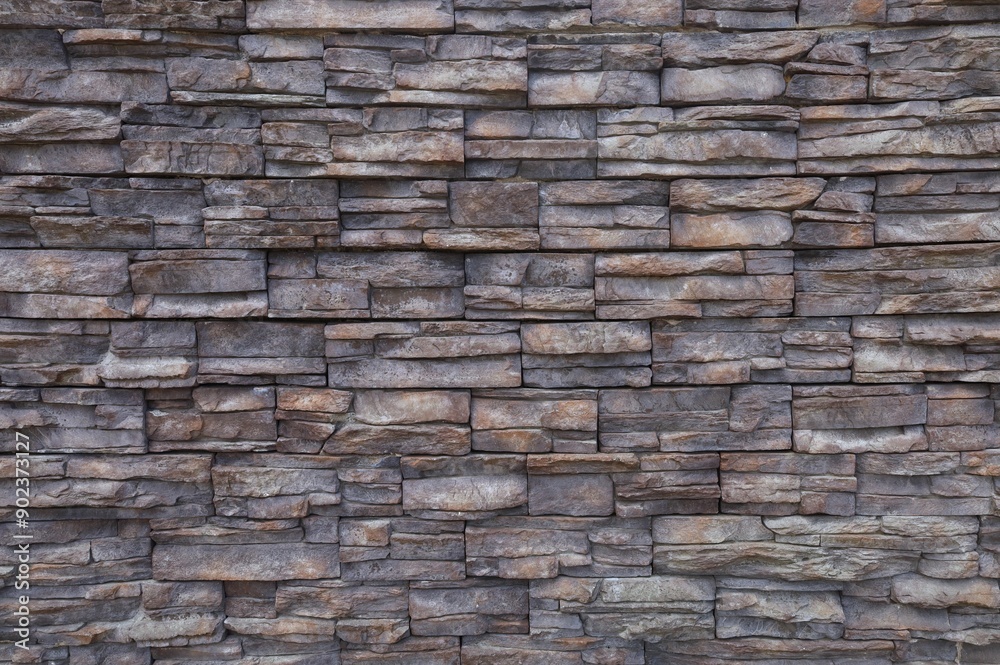 Dark brown stone coating wall made of striped stacked slabs of natural rocks. Panels for exterior. Background and texture. Dark brown stone coating wall made of striped stacked slabs of natural rocks. Panels for exterior. Background and texture.