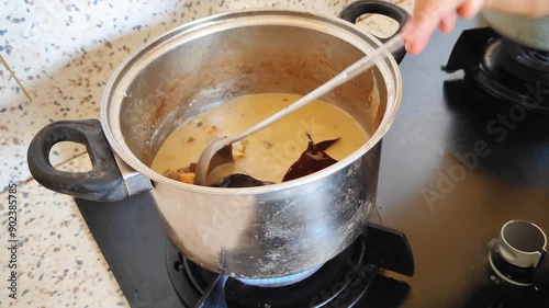 Woman's hand cooking beef curry (Gulai babat and iso sapi) photo