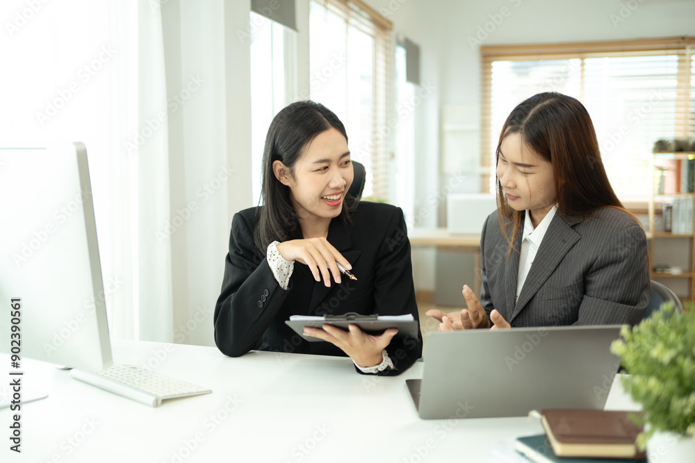 Two smiling business colleagues reviewing marketing reports and discussing project plan at office Two smiling business colleagues reviewing marketing reports and discussing project plan at office