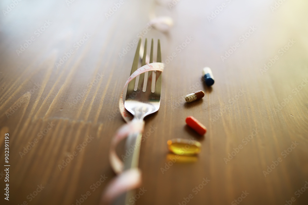 Fork with Measuring Tape and Various Pills on Wooden Table Symbolizing Diet and Health Choices Fork with Measuring Tape and Various Pills on Wooden Table Symbolizing Diet and Health Choices