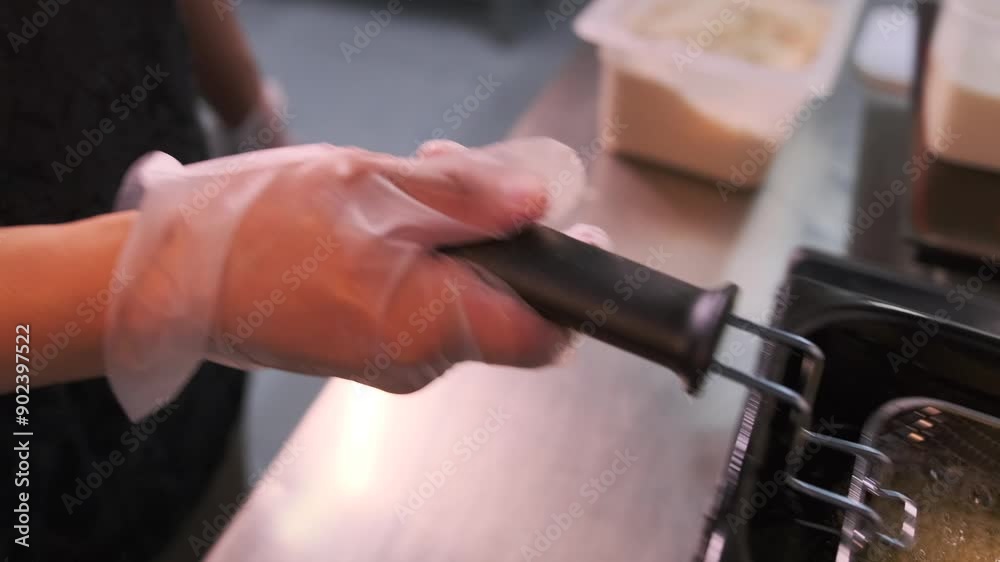 Chef hand in white glove preparing food in boiling oil in the restaurant kitchen close up. Chef hand in white glove preparing food in boiling oil in the restaurant kitchen close up.