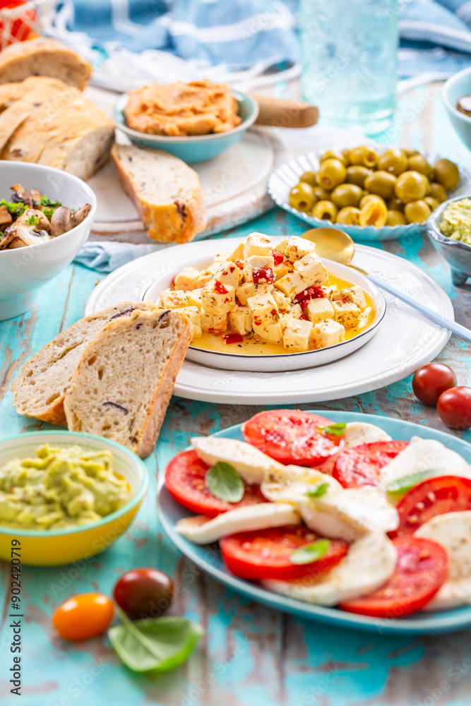 Picnic table with assorted appetizers, raw vegetables, cheese, dips, baguette and pastrami and serrano platter Picnic table with assorted appetizers, raw vegetables, cheese, dips, baguette and pastrami and serrano platter