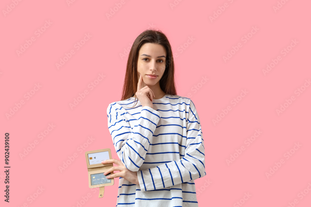 Thoughtful young woman with credit card holder on pink background Thoughtful young woman with credit card holder on pink background