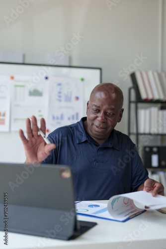 Happy African American businessman working with documents, preparing reports or marketing analysis, financial calculations. Working on a laptop computer online Contacting customers in a modern office