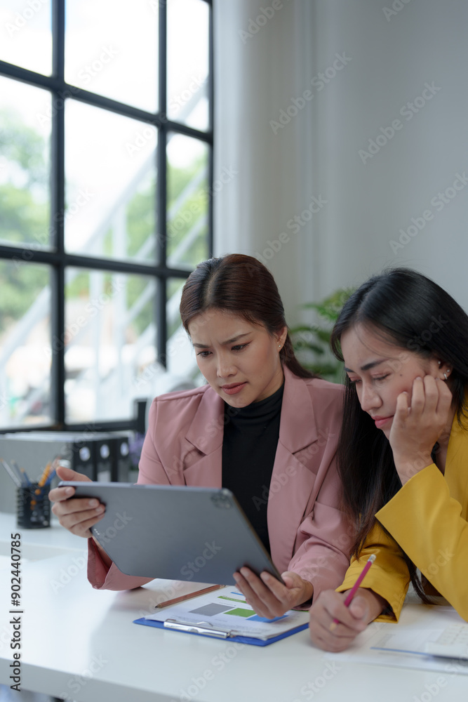 Asian businesswoman who is working hard and stressed Headache over financial paperwork with co-workers while sitting at desk in office, Office Syndrome concept. Asian businesswoman who is working hard and stressed Headache over financial paperwork with co-workers while sitting at desk in office, Office Syndrome concept.