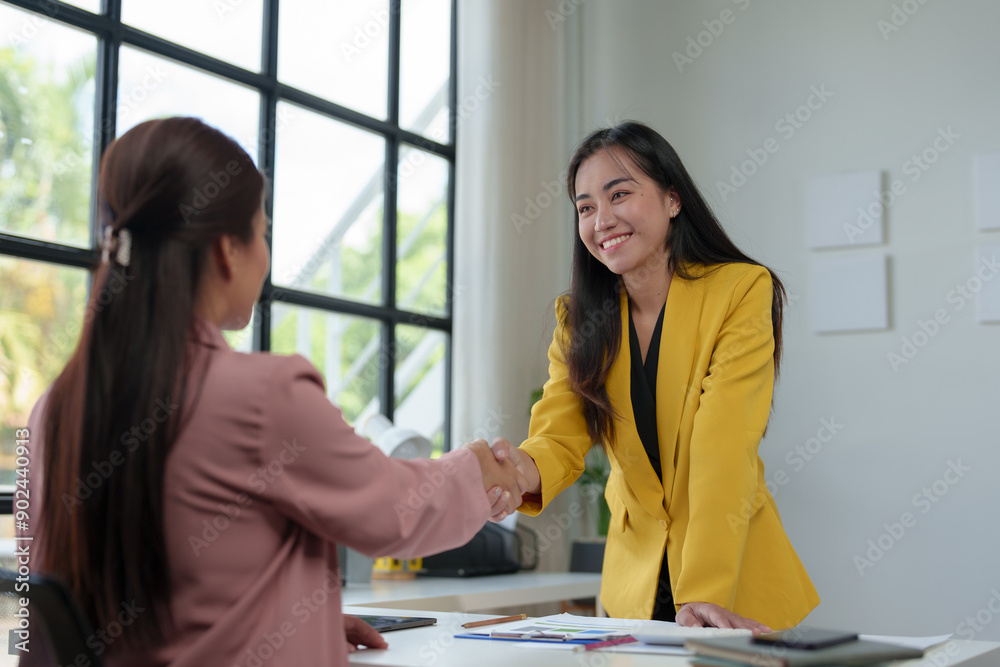 Two beautiful businesswomen smiling happily and confidently shake hands to agree on a joint venture in the field of business finance investment at the office. Two beautiful businesswomen smiling happily and confidently shake hands to agree on a joint venture in the field of business finance investment at the office.