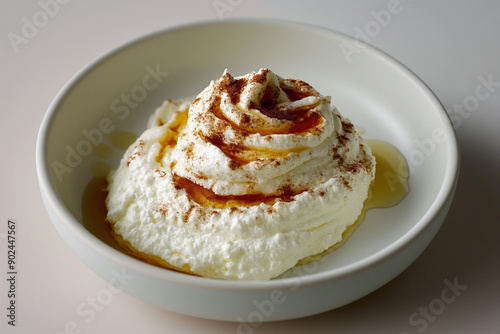 A dollop of creamy whipped feta cheese, swirled with a drizzle of fiery-sweet hot honey, sits invitingly on a minimalist background. This trendy appetizer is sure to tantalize taste buds. photo