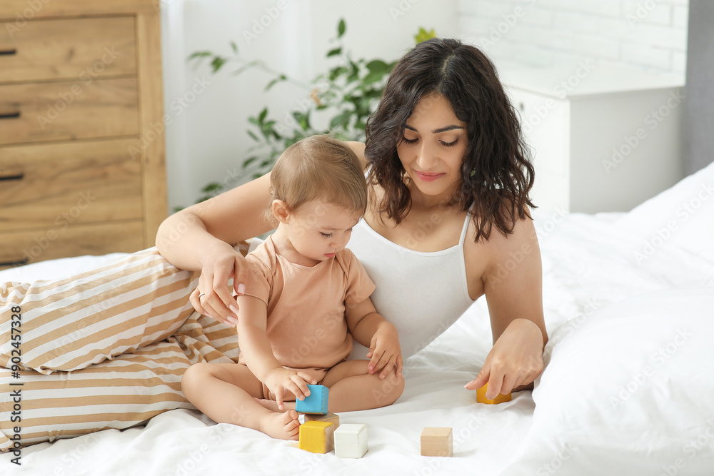 Happy mother and her little baby playing with cubes on bed at home Happy mother and her little baby playing with cubes on bed at home