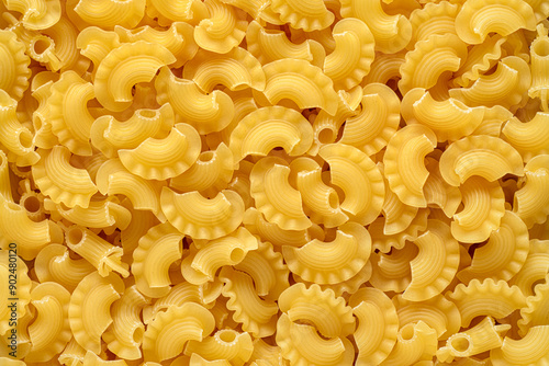 Creste di gallo pasta spread out on a textured surface or background.