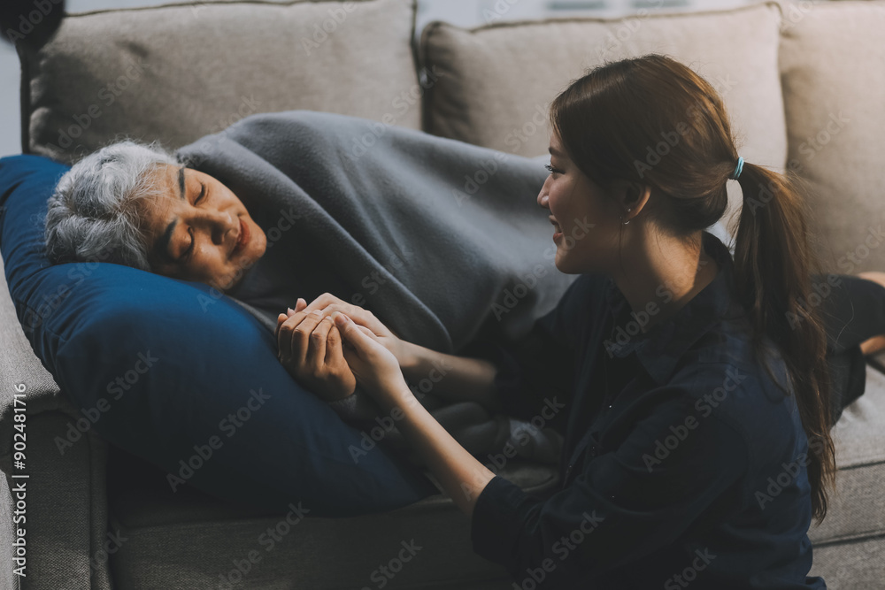 Fototapeta premium happy family Granddaughter takes care of her grandmother with warm cloths sitting on the sofa.
