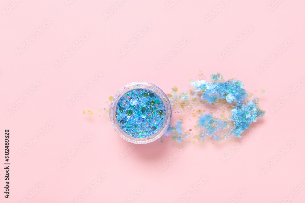 Jar of blue glitter with stroke on pink background Jar of blue glitter with stroke on pink background